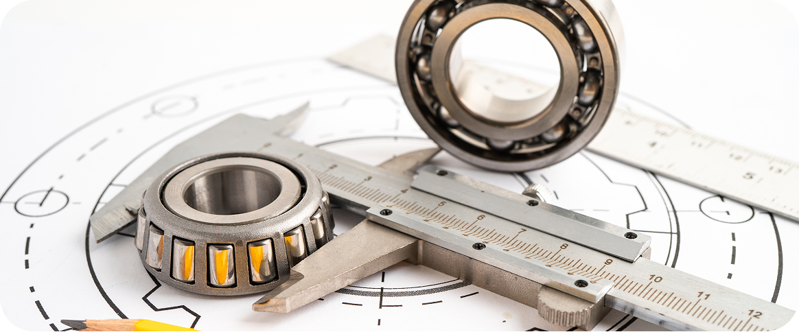 Vernier caliper measuring a ball bearing on engineering blueprints